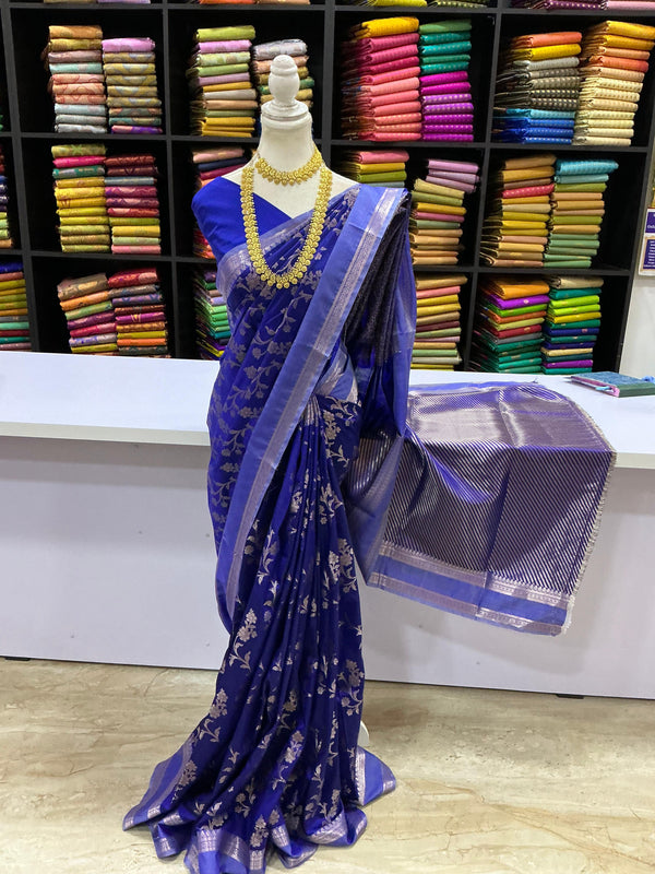 Blue saree with silver patterns on a mannequin against a colorful fabric background